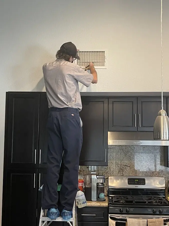 Technician inspecting an air vent during HVAC service in Monroe
